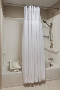 a white shower curtain in a bathroom with a tub at SpringHill Suites by Marriott Syracuse Carrier Circle in East Syracuse