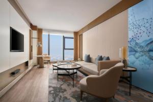 Jinhua Marriott Hotel في Jinhua: غرفة معيشة مع أريكة وطاولة