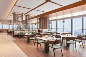 um restaurante com mesas e cadeiras e janelas grandes em Jinhua Marriott Hotel em Jinhua