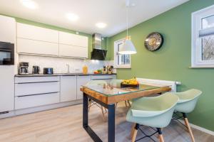 cocina con paredes verdes, mesa de madera y sillas en Suite Wind & Wellen, en Zingst