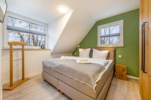 1 dormitorio con 1 cama con paredes y ventanas verdes en Suite Wind & Wellen, en Zingst