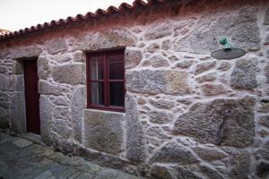 un edificio de piedra con ventana y luz en Casas dos Avos, en Vale de Cambra