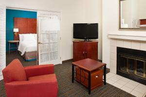 ein Hotelzimmer mit einem Bett, einem TV und einem Stuhl in der Unterkunft Residence Inn Ontario Airport in Ontario