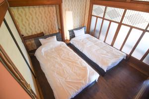 two twin beds in a room with two windows at 山鹿師蔵 in Yamaga