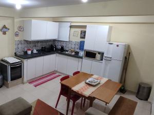 a kitchen with white cabinets and a table and a microwave at Estúdio Mobiliado em Poços in Poços de Caldas
