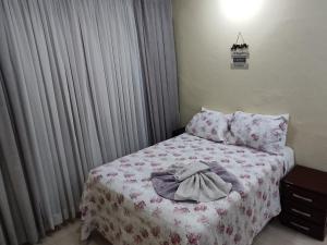 a bedroom with a bed with a blanket and curtains at Estúdio Mobiliado em Poços in Poços de Caldas