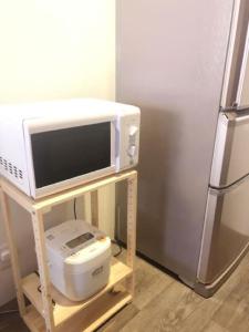 un forno a microonde su un supporto accanto a un frigorifero di J and H 名駅南貸切一軒家 a Nagoya