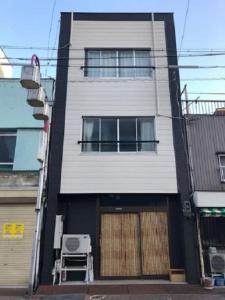 un alto edificio bianco con porta e finestre di J and H 名駅南貸切一軒家 a Nagoya