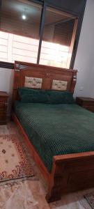 a bedroom with a wooden bed with a green comforter at Tamraght agadir in Tamraght Ouzdar