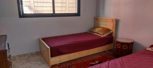 a bedroom with a wooden bed and a window at Tamraght agadir in Tamraght Ouzdar