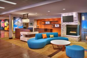 Fairfield Inn & Suites by Marriott Salt Lake City Midvale في ميدفال: غرفة معيشة مع أريكة زرقاء ومدفأة