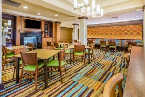 a dining room with tables and chairs and a fireplace at Fairfield Inn and Suites Turlock in Turlock