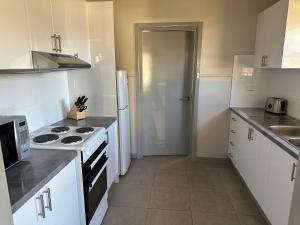 a kitchen with white cabinets and a stove top oven at Copper City Motel in Cobar