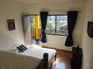 een slaapkamer met een bed en een groot raam bij Hotel Brisas del Nevado in Güicán