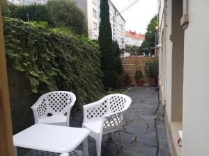 Duas cadeiras brancas e uma mesa num pátio em Apartamento con pequeño jardín en el centro em Ferrol
