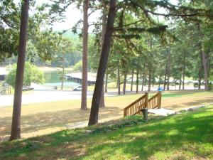 una panchina di legno seduta in un parco alberato di Mountain Harbor King Guest Room on Lake Ouachita a Mount Ida