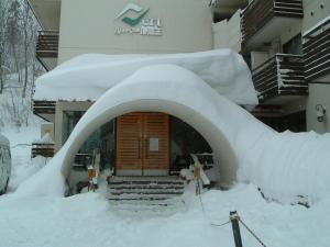 pokryte śniegiem wejście do budynku z stosem śniegu w obiekcie Le Vert Zao w mieście Zaō Onsen