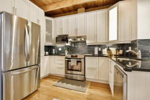 a kitchen with white cabinets and a stainless steel refrigerator at STUNNING full APARTMENTS - stocked KITCHENS - WASHER & DRYERS - WORKSPACE PROVIDED - FAST WIFI - LOCATED on the FAMOUS ST Denis street - Near METRO MONT ROYAL in Montreal