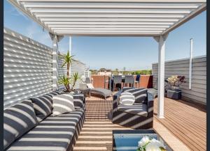 a patio with a white pergola and couches on a deck at Modern 3 bedroom apartment, beach, surf & shops in Cape Woolamai