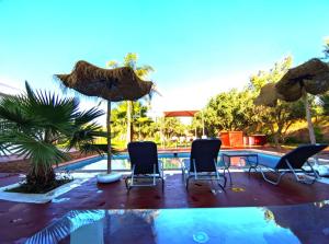 un patio avec des chaises et des parasols à côté d'une piscine dans l'établissement Villa Dar Sukar, à Marrakech