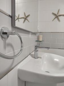 een witte badkamer met een wastafel en een spiegel bij Casa Hurtere in Horta