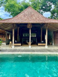 a pavilion with a swimming pool in front of it at Bohio Villas Gili Air in Gili Islands