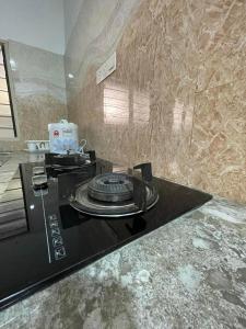 a kitchen with a black stove top with a stone wall at Four Rooms Homstay 'A' With Wifi And Smart TV in Wakaf Tapai in Wakaf Tapai