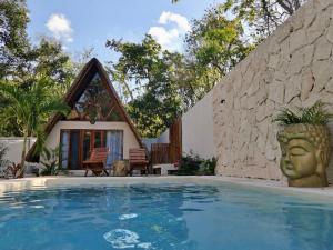 a villa with a swimming pool in front of a house at Lodge Tzunum Jade in Tulum