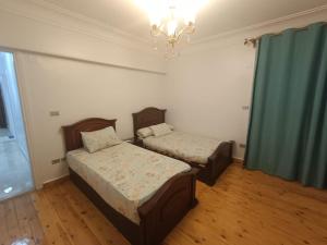 een slaapkamer met 2 bedden en een kroonluchter bij Apartment closes to city stars شقة فخمة من سيتي ستارز in Caïro