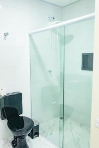 a glass shower with a black toilet in a bathroom at Hotel Tenda Obsession in Sao Paulo