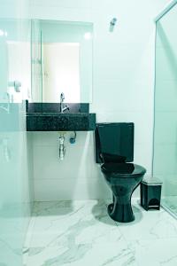 a bathroom with a black toilet and a sink at Hotel Tenda Obsession in São Paulo