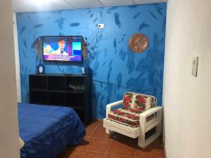 1 dormitorio con pared azul, silla y TV en Zut2 en Tandil