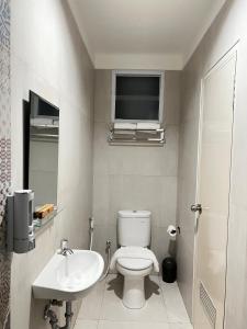 TV y baño con aseo y lavamanos. en CASA CALMA HOTEL en Yakarta