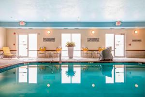 una piscina en un hotel con sillas y mesas en Fairfield Inn Green Bay Southwest en Green Bay
