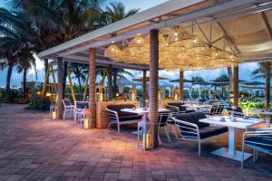 ein Restaurant am Strand mit Tischen und Stühlen in der Unterkunft Fort Lauderdale Marriott Pompano Beach Resort and Spa in Pompano Beach