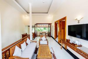 a living room with white furniture and a flat screen tv at Tirtodipuran Hotel Yogyakarta in Timuran