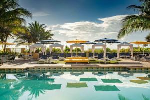 einen Pool mit Sonnenschirmen, Stühlen und Tischen in der Unterkunft Fort Lauderdale Marriott Pompano Beach Resort and Spa in Pompano Beach