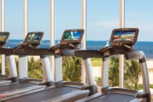 una fila de máquinas de cintas de correr con el océano en el fondo en Fort Lauderdale Marriott Pompano Beach Resort and Spa, en Pompano Beach