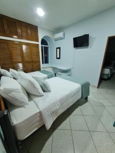 1 dormitorio con 4 camas y TV de pantalla plana en Casa Blanca del Mar, en Santa Marta