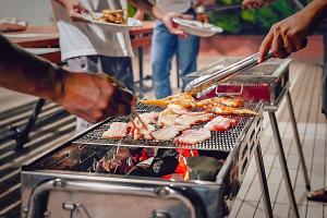 a group of people cooking food on a grill at Hotel Kailani in Oshima