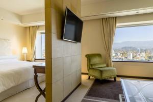um quarto de hotel com uma cama, uma televisão e uma cadeira em Sheraton Mendoza Hotel em Mendoza
