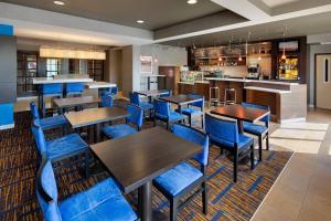 a restaurant with blue chairs and tables and a bar at Courtyard Grand Rapids Airport in Grand Rapids