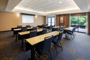 a conference room with tables and chairs and a screen at Courtyard Grand Rapids Airport in Grand Rapids