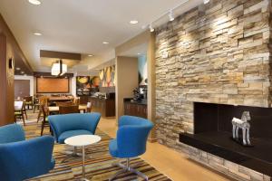 a lobby with a fireplace and blue chairs at Fairfield Inn Colorado Springs Air Force Academy in Colorado Springs