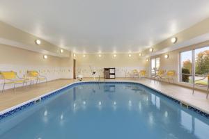 a swimming pool in a hotel with yellow chairs and tables at Fairfield Inn Colorado Springs Air Force Academy in Colorado Springs