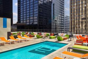 a pool on the roof of a building with chairs and tables at Aloft Houston Downtown in Houston