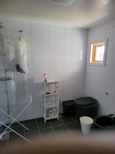 Fritidshus på backstigen 3 i Surahammar في Surahammar: حمام من البلاط الأبيض مع مرحاض ورف