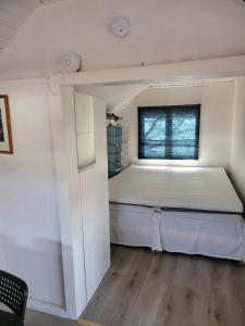 Cama en habitación pequeña con ventana en Fritidshus på backstigen 3 i Surahammar, en Surahammar