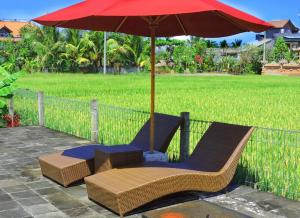 a pair of chairs under an umbrella on a patio at Pondok Ayu Soca in Ubud