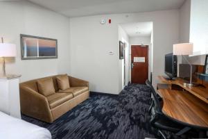une chambre d'hôtel avec un canapé et une télévision dans l'établissement Fairfield Inn & Suites by Marriott Charleston North/Ashley Phosphate, à Charleston